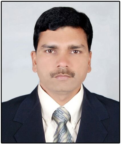 Portrait of Dr. Kapoor wearing traditional attire with academic books in background